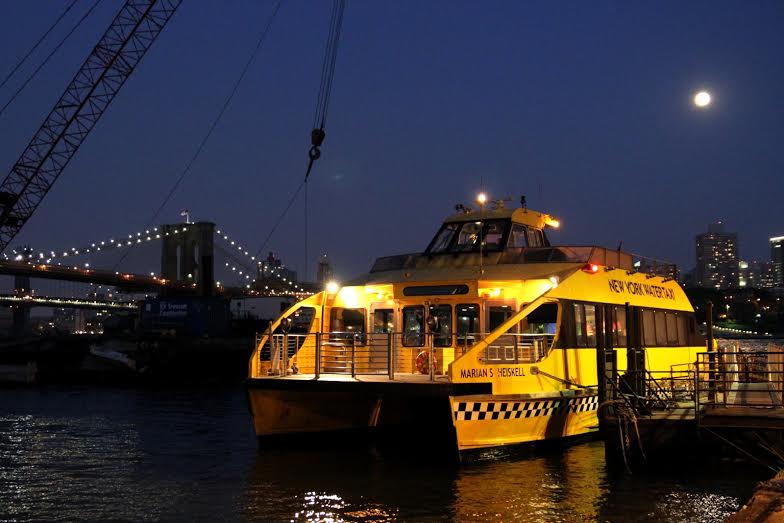 A New York Water Taxi in front of the Brooklyn and Manhattan Bridges