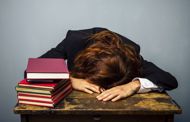 Businesswoman sleeping next to stack of books