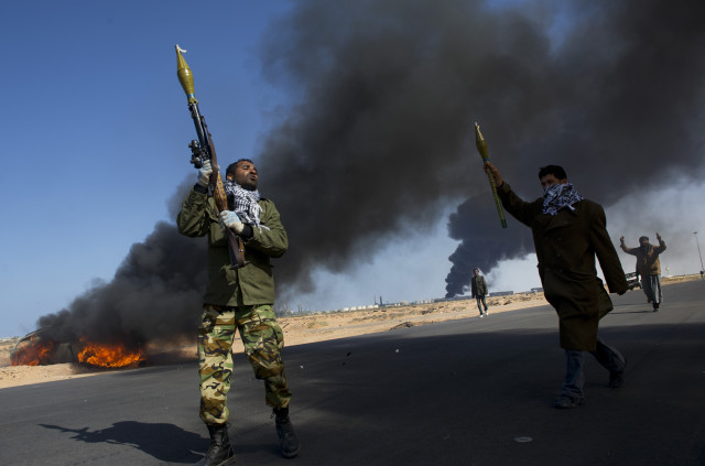 Opposition troops burn tires to use as cover during heavy fighting, shelling, and airstrikes near the main checkpoint near the refinery in Ras Lanuf as rebel troops pull back from Ras Lanuf, in Eastern Libya, March 11, 2011. Qaddafi's troops have been advancing East, and re-taking territory that had previously fallen to the rebels, as they batter the rebels with artillery and air strikes. (Credit: Lynsey Addario for The New York Times)