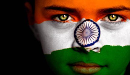 Portrait of a boy with the flag of India painted on his face.
